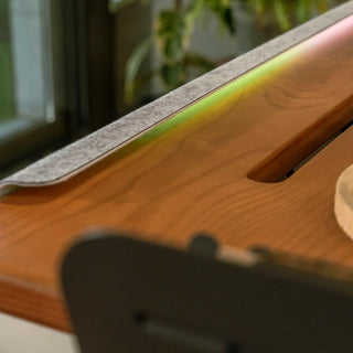 Close-up of a desk light with a reflective on a beflo Tenon wooden surface.